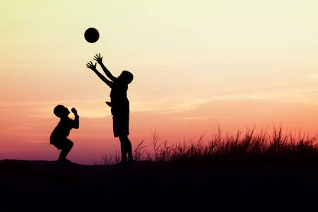 children playing ball on meadow, sunset, summertimeの写真素材