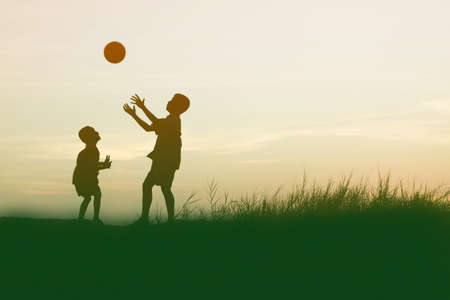 children playing ball on meadow, sunset, summertimeの写真素材