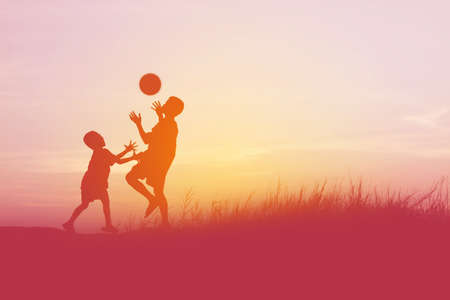 children playing ball on meadow, sunset, summertimeの写真素材
