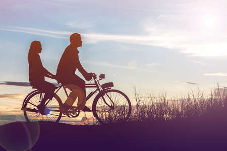 silhouette of couple driving bike happy time sunsetの写真素材