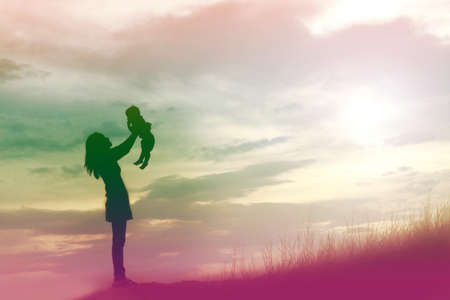 Mother encouraged her son outdoors at sunset, silhouette conceptの写真素材
