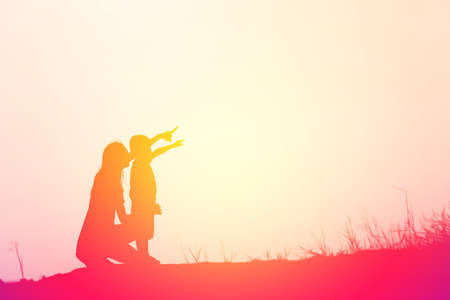 Mother encouraged her son outdoors at sunset, silhouette conceptの写真素材