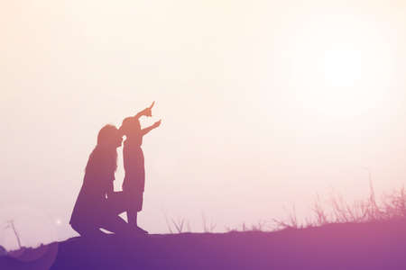 Mother encouraged her son outdoors at sunset, silhouette conceptの写真素材