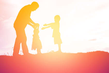 Silhouettes of father and little daughter walking at sunsetの写真素材