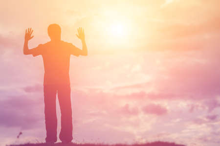 Silhouette of woman praying over beautiful sky backgroundの写真素材