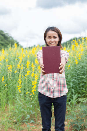 Woman holding a book in the sun in the morning, nice atmosphere.の写真素材
