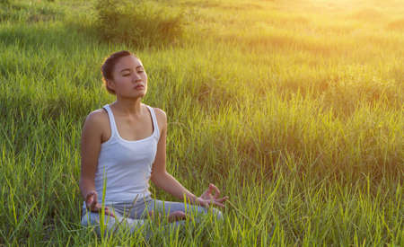 Yoga in the city: beautiful young fit woman wearing sportswear meditating, breathing, sitting with crossed legs in Half Lotus Posture on the street on summer day, Ardha Padmasana, copy spaceの写真素材