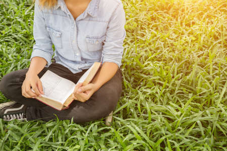 Woman holding a book in meadows on the sunshine of morning.の写真素材