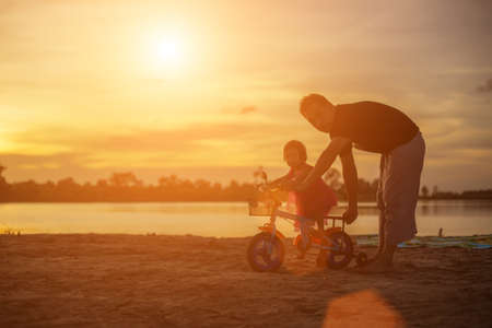 Father took the baby learn to walk at sunset.の写真素材