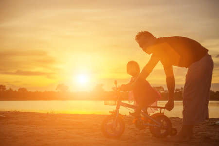 Father took the baby learn to walk at sunset.の写真素材