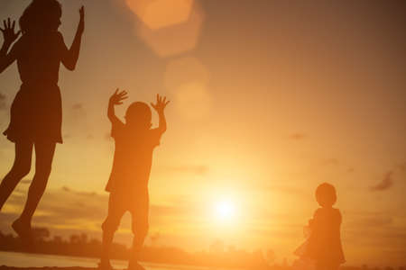 Silhouettes of mother and little daughter walking at sunsetの写真素材