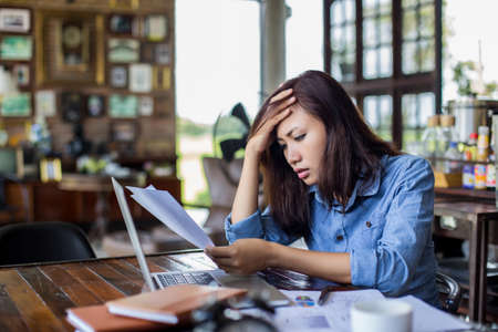 Young woman sitting in a cafe with her laptop, Stressful for work.の写真素材