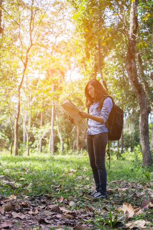 Women hiker with backpack checks map to find directions in wilderness areaの写真素材