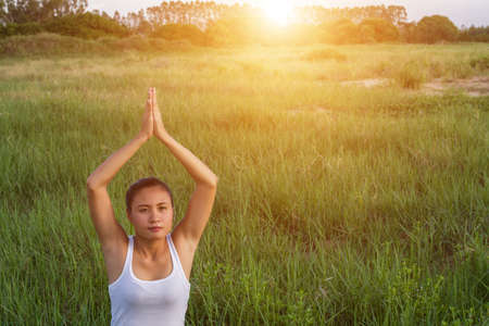 Yoga in the city: beautiful young fit woman wearing sportswear meditating, breathing, sitting with crossed legs in Half Lotus Posture on the street on summer day, Ardha Padmasana, copy spaceの写真素材