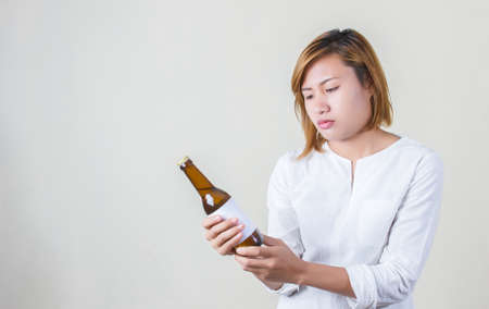 Cheerful charming fitness girl in pink top showing a bottle of water over white backgroundの写真素材