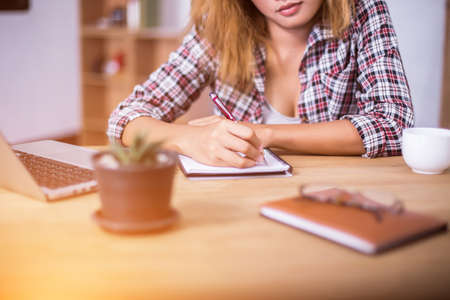 business woman writing something on notepad in office.の写真素材