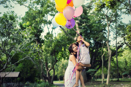 mom carrying his daughter with nature and sunlight, enjoyment family.の写真素材