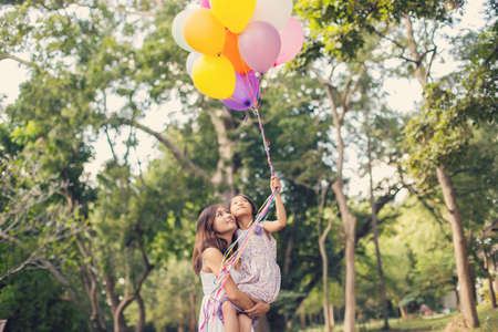 mom carrying his daughter with nature and sunlight, enjoyment family.の写真素材