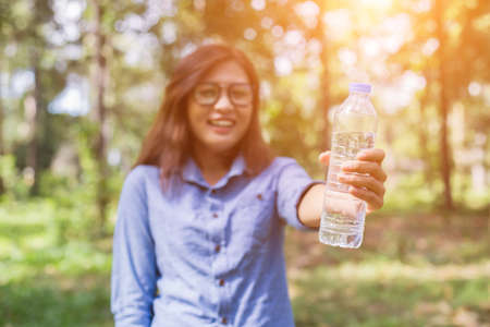 Beautiful young woman drinking water in the morning after finished jogging