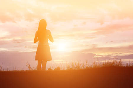 Silhouette of woman praying over beautiful sky backgroundの写真素材