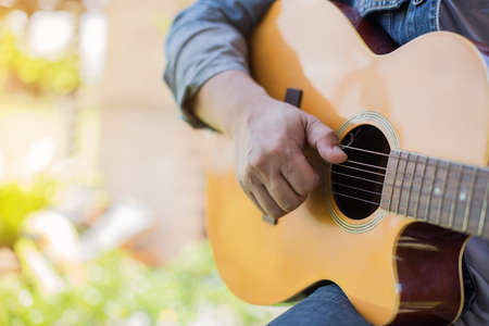 Young hipster man playing guitar to relaxing on his holiday, enjoy with natural and fresh air.