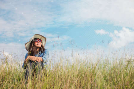 Sad young girl sitting alone on a grass outdoors,Sadness. Lonelinessの写真素材