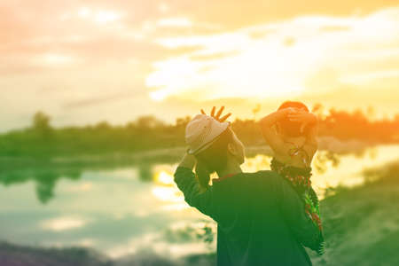 a silhouette of a happy young girl child the arms of his loving mother for a hug, in front of the sunset in the sky on a summer day.の写真素材