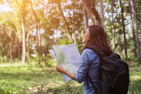 Women hiker with backpack checks map to find directions in wilderness areaの写真素材