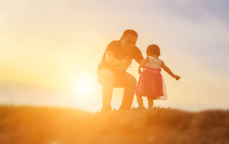 Father took the baby learn to walk at sunset.の写真素材
