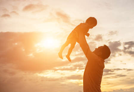 Father took the baby learn to walk at sunset.の写真素材