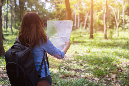 Women hiker with backpack checks map to find directions in wilderness area