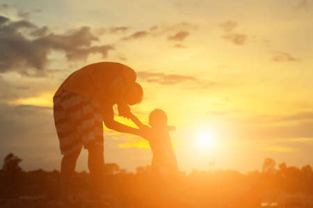 Happy dad throws the baby at sunsetの写真素材