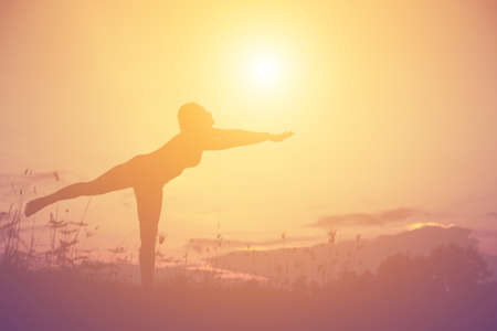 Silhouette of woman praying over beautiful sky backgroundの写真素材