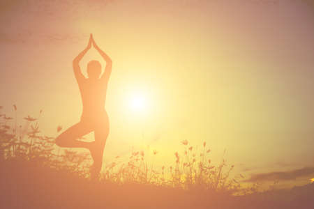 Silhouette of woman praying over beautiful sky backgroundの写真素材