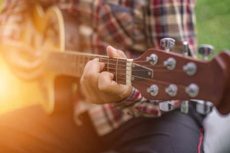 Young hipster man playing guitar to relaxing on his holiday, enjoy with natural and fresh air.の写真素材