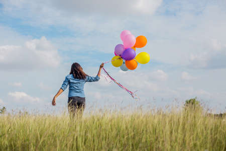 Beautiful Girl jumping with balloons on the beachの写真素材