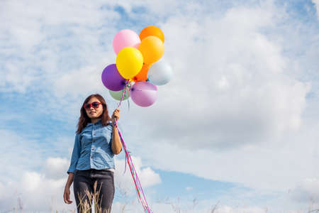 Beautiful Girl jumping with balloons on the beachの写真素材