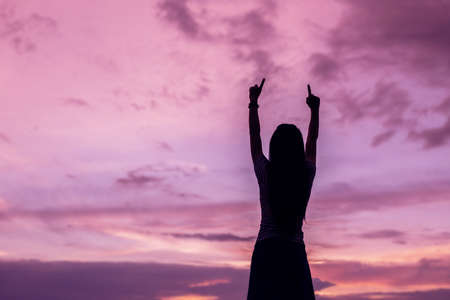 Silhouette of woman praying over beautiful sky background