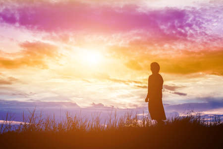 Silhouette of woman praying over beautiful sky backgroundの写真素材