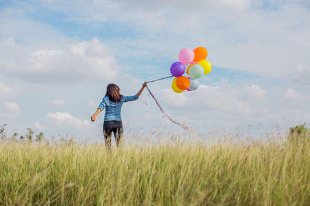 Beautiful Girl jumping with balloons on the beachの写真素材