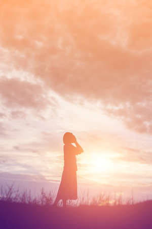 Silhouette of woman praying over beautiful sky backgroundの写真素材