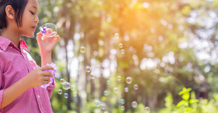 Cute little girl wearing a pink shirt blowing bubbles in the park,vintage style.の写真素材
