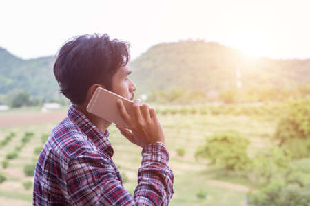 Young hipster bearded man talking on phone, smiling, outside mountain view.の写真素材