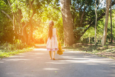 Cute little girl sitting swings , teddy bear sitting with her,little girl pointed to the tree.の写真素材