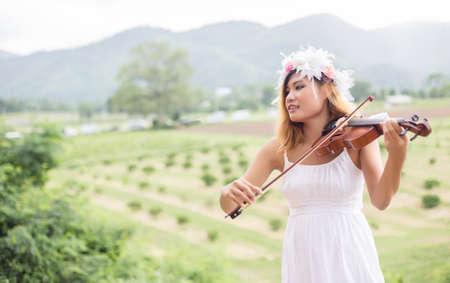 Young hipster musician woman playing violin in the nature outdoor lifestyle behind mountain.の写真素材