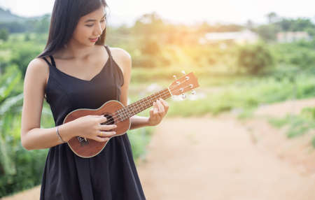 Beautiful woman holding a guitar on his shoulder, Nature park summer outside.の写真素材