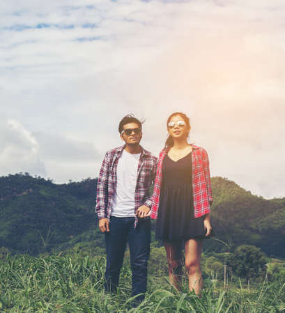 Young hipster couple holding hands walking on the meadow relaxing and natural atmosphere is very natural.の写真素材