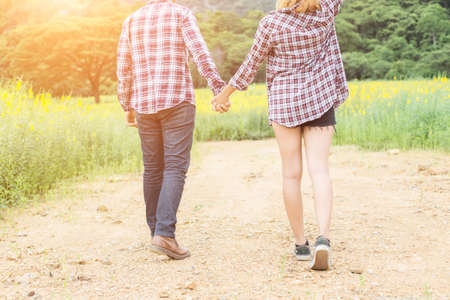 Young hipster couple relaxing in yellow flower field at summer. Enjoying with nature.の写真素材