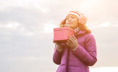 Happy young woman with gift in hands. Christmas and winter concept.の写真素材