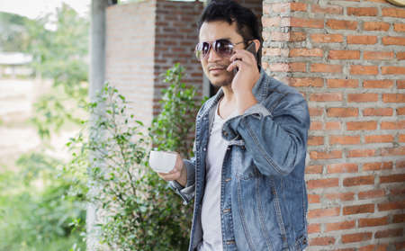 Young man with smartphone smiling relaxing at cafe.